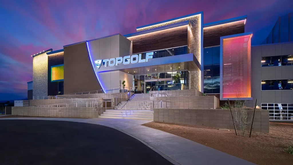 Modern TOPGOLF building lit against a vibrant twilight sky.