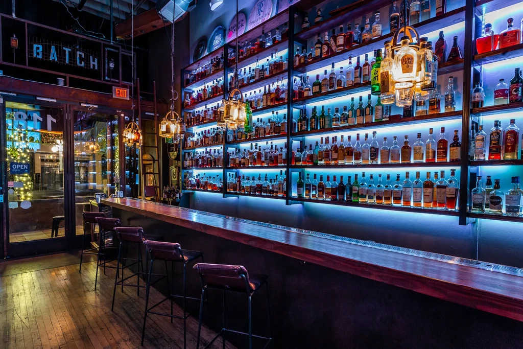 Stylish bar interior with blue-lit liquor shelves and warm pendant lights.
