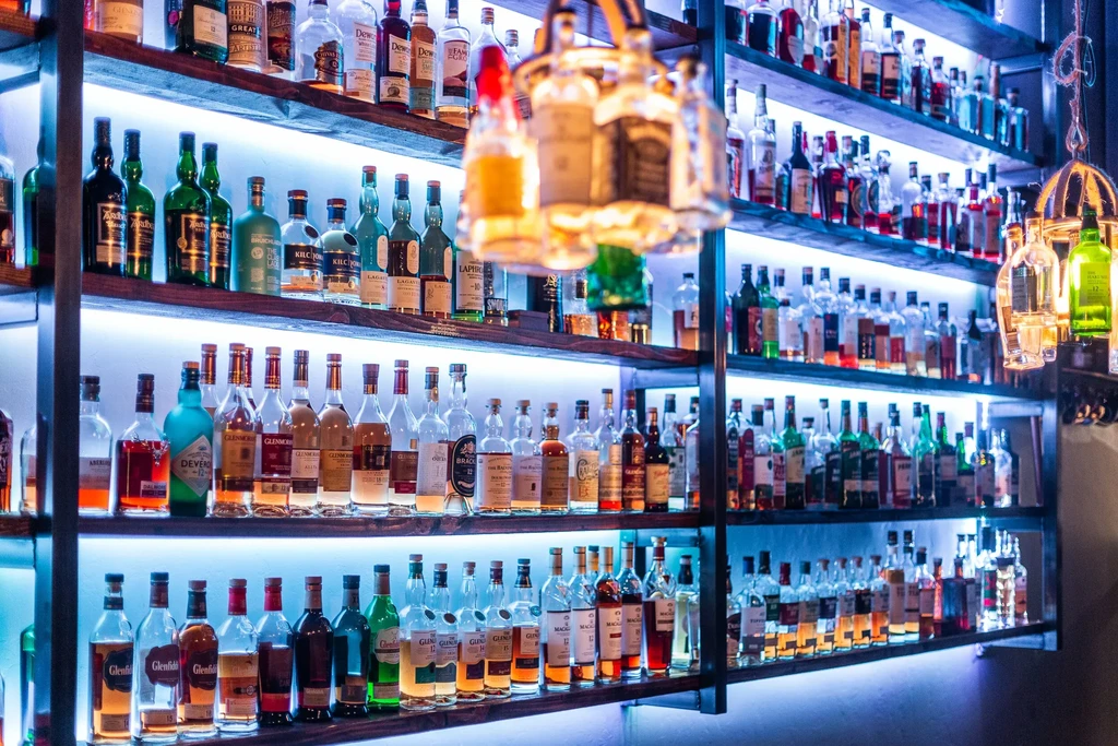 Well-stocked bar with illuminated shelves of diverse liquor bottles.