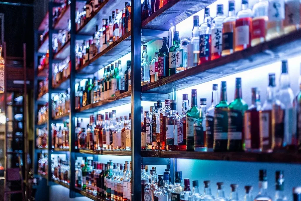 Extensive bar display of spirits lit by cool blue-purple LEDs.