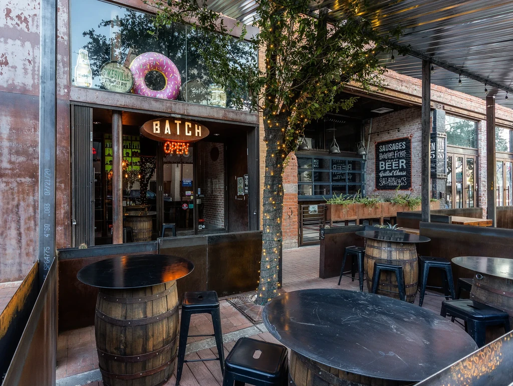 Rustic BATCH restaurant patio with barrel tables and string lights.