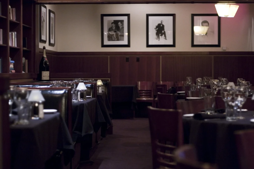 Upscale restaurant interior with set tables, booths, and warm, dim lighting.