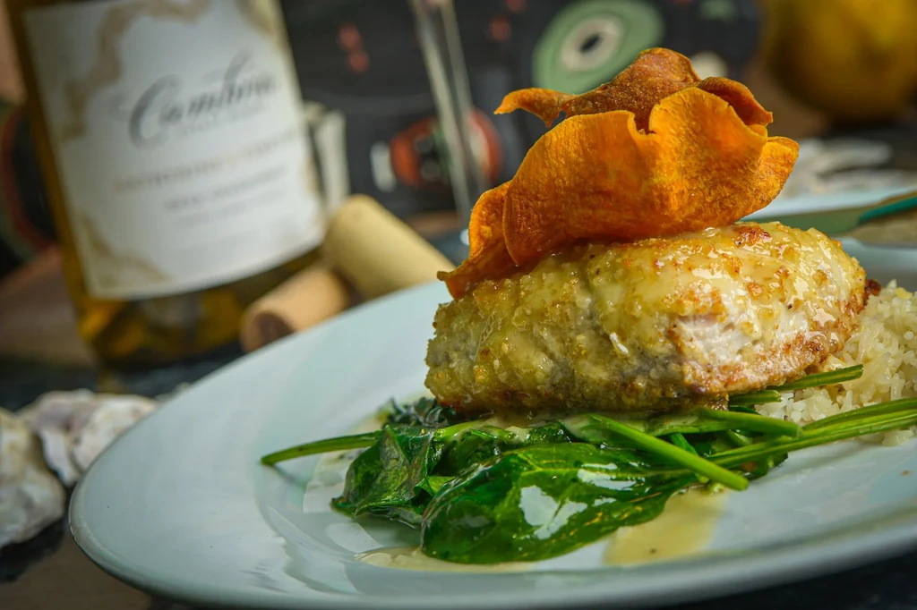 Plated golden-crusted fish, orange crisps, rice, and dark greens.