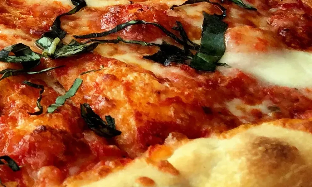 Close-up of a Margherita pizza with melted cheese and fresh basil.