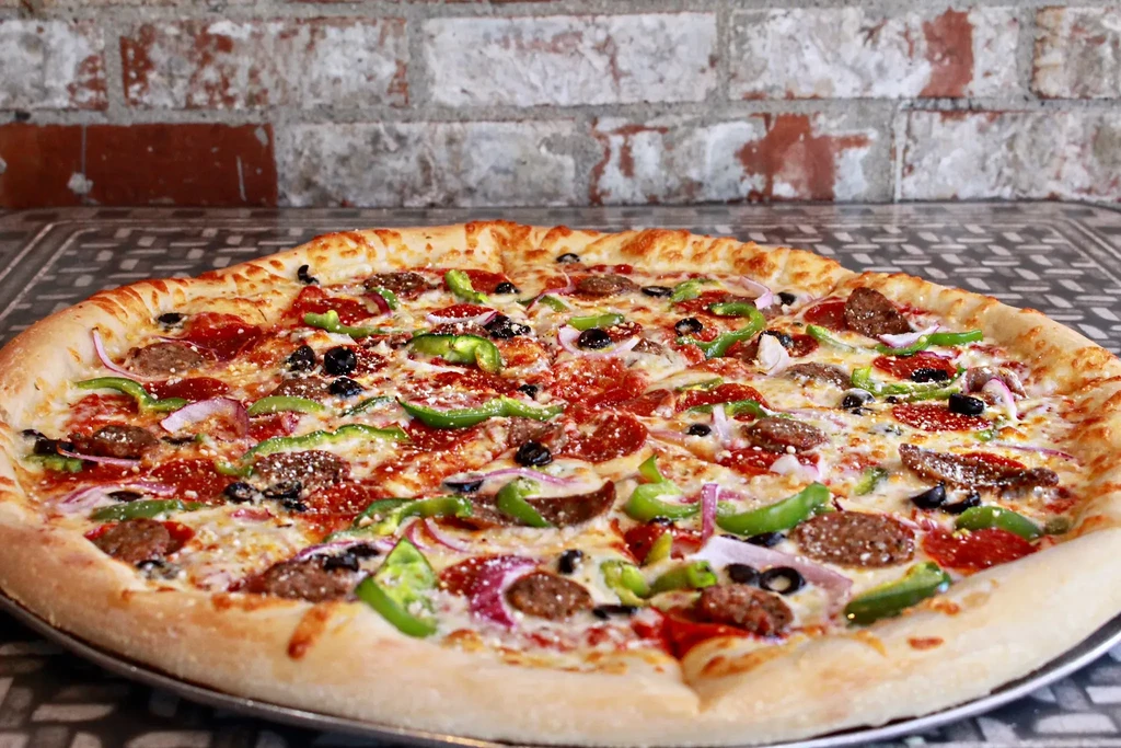 Baked pizza with pepperoni, sausage, peppers, onions, olives, and cheese.