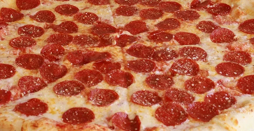 Overhead close-up of a pepperoni pizza with melted mozzarella and crispy pepperoni.