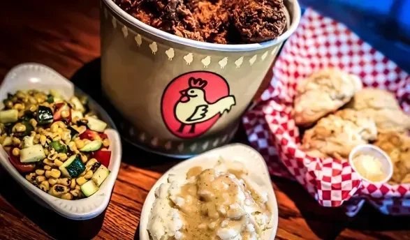 Overhead shot of fried chicken, corn salad, mashed potatoes, and biscuits.