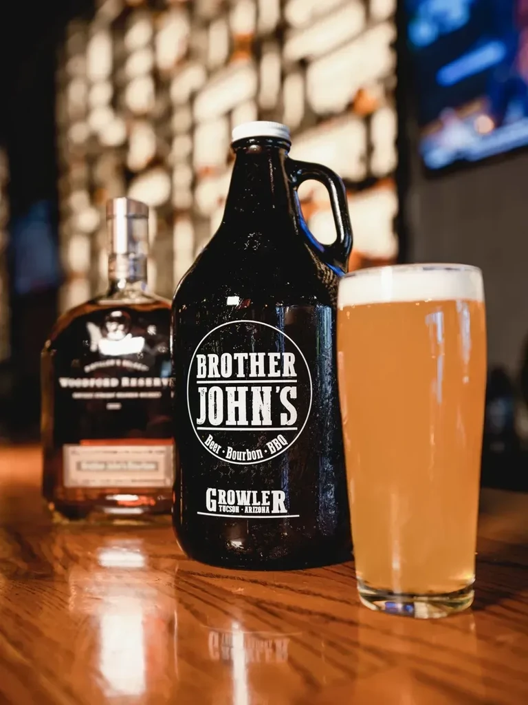 Bourbon, Brother John's growler, and beer pint on a wooden bar.