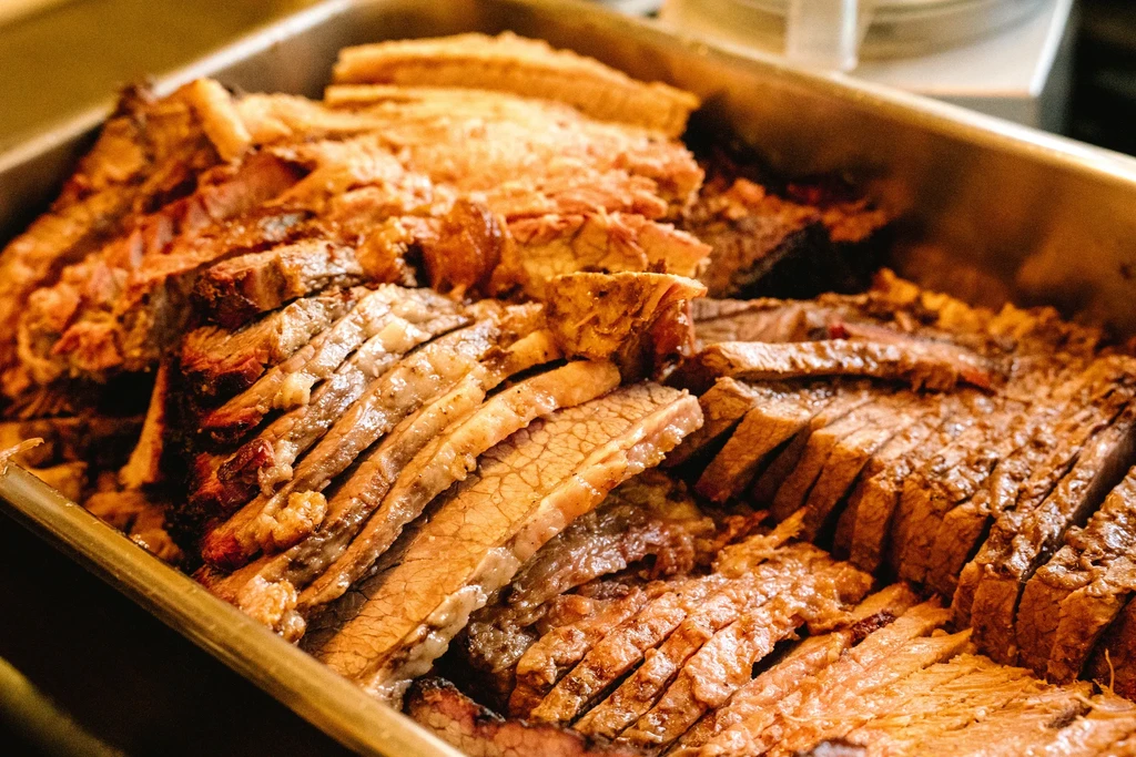 A large tray of moist, sliced, slow-cooked brisket with bark.