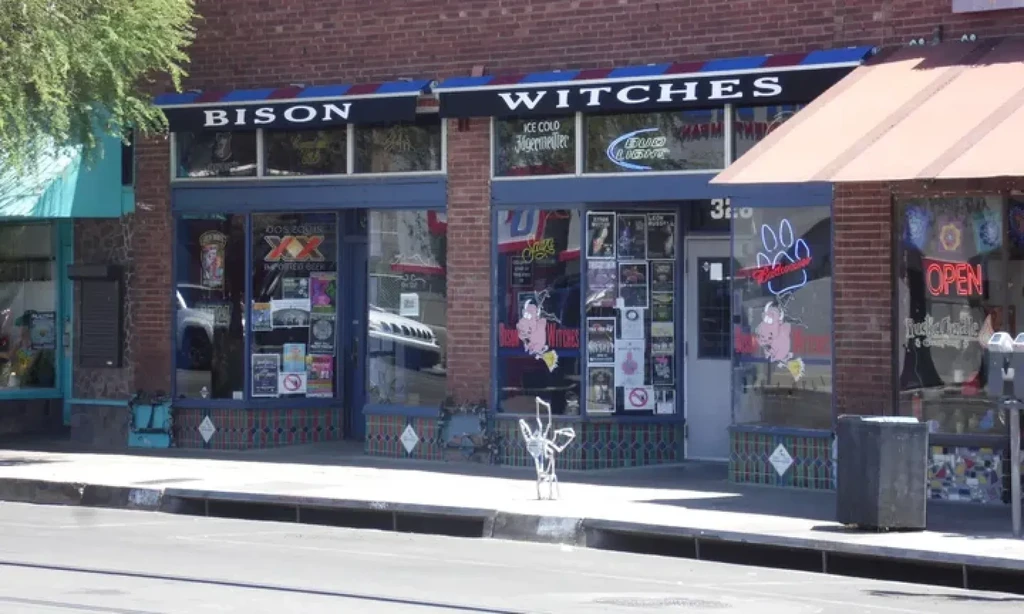 BISON WITCHES storefront with red brick, blue awnings, and beer ads.