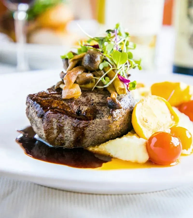 Seared steak with mushrooms, microgreens, mashed potatoes, and cherry tomatoes.