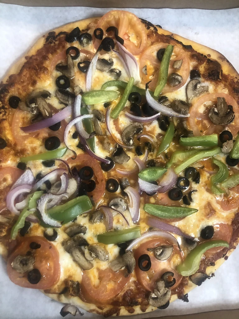 Close-up of a freshly baked, round pizza with colorful vegetables.