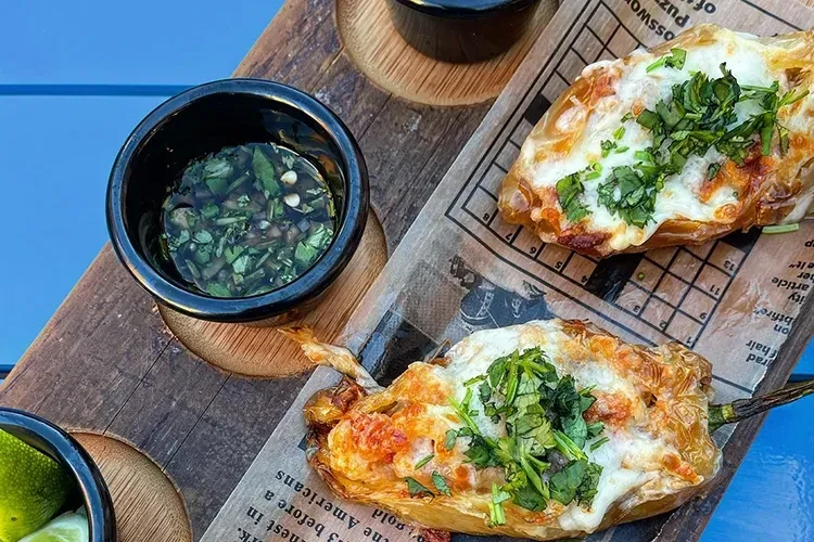Two baked chili peppers, melted cheese, cilantro, sauce, and lime.