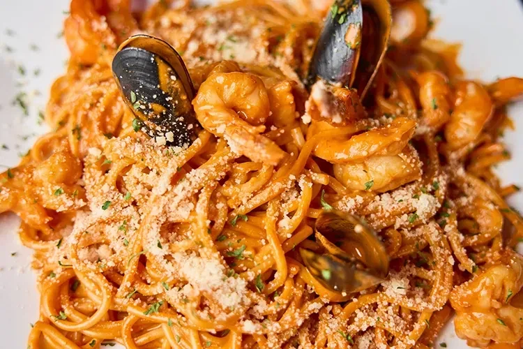 Seafood pasta with shrimp, mussels, creamy sauce, Parmesan, and herbs.