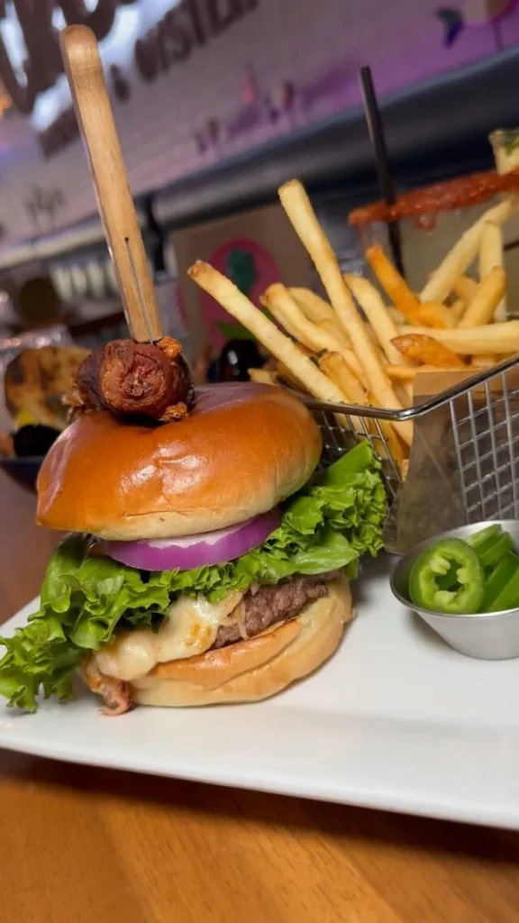 Close-up gourmet burger, french fries, and jalapeños on a plate.