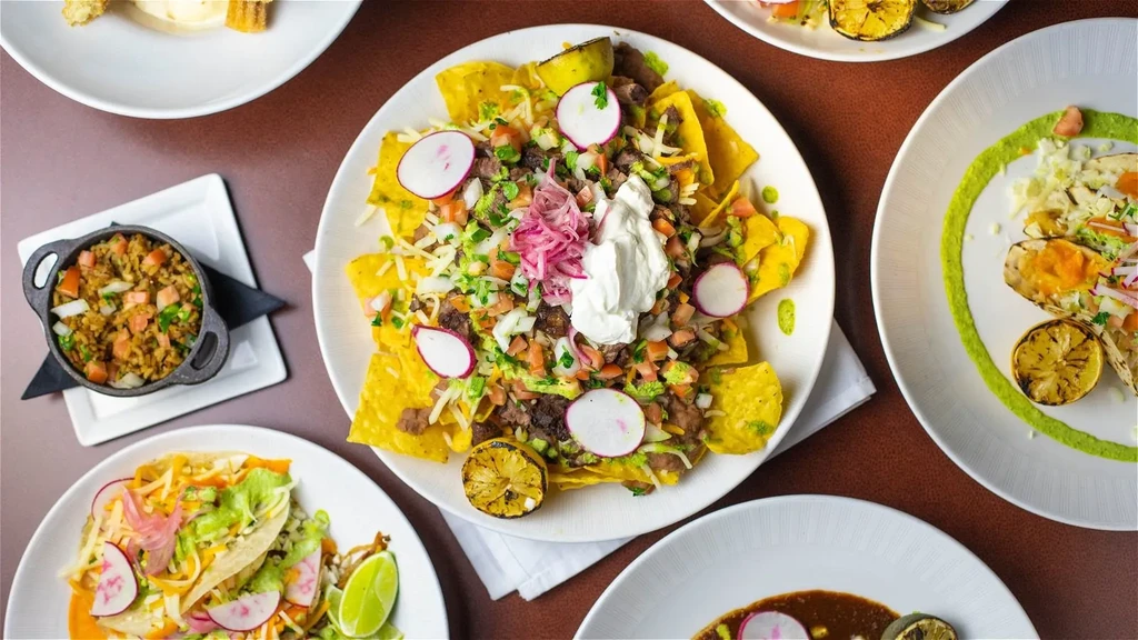 Overhead view of a vibrant table with loaded nachos and Mexican dishes.