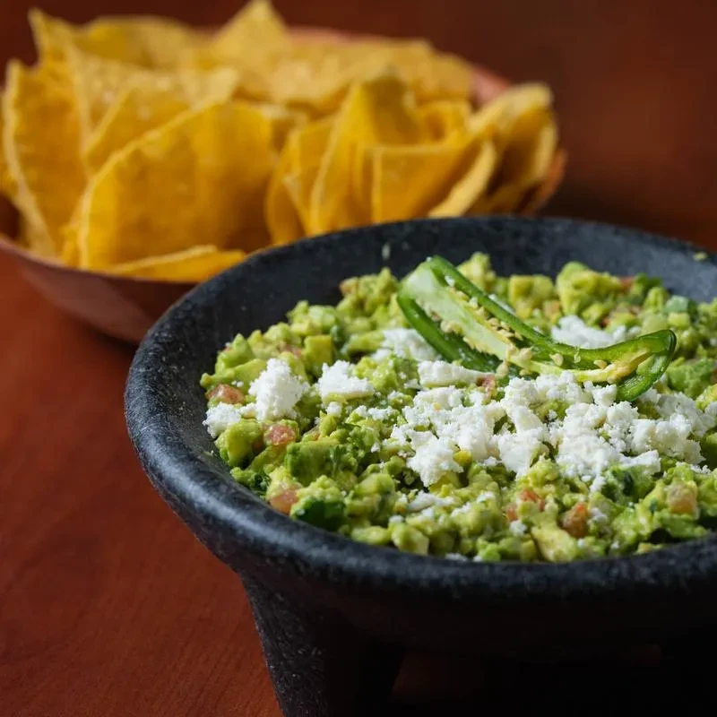 Fresh, chunky guacamole with cheese, jalapeño slices, and tortilla chips.