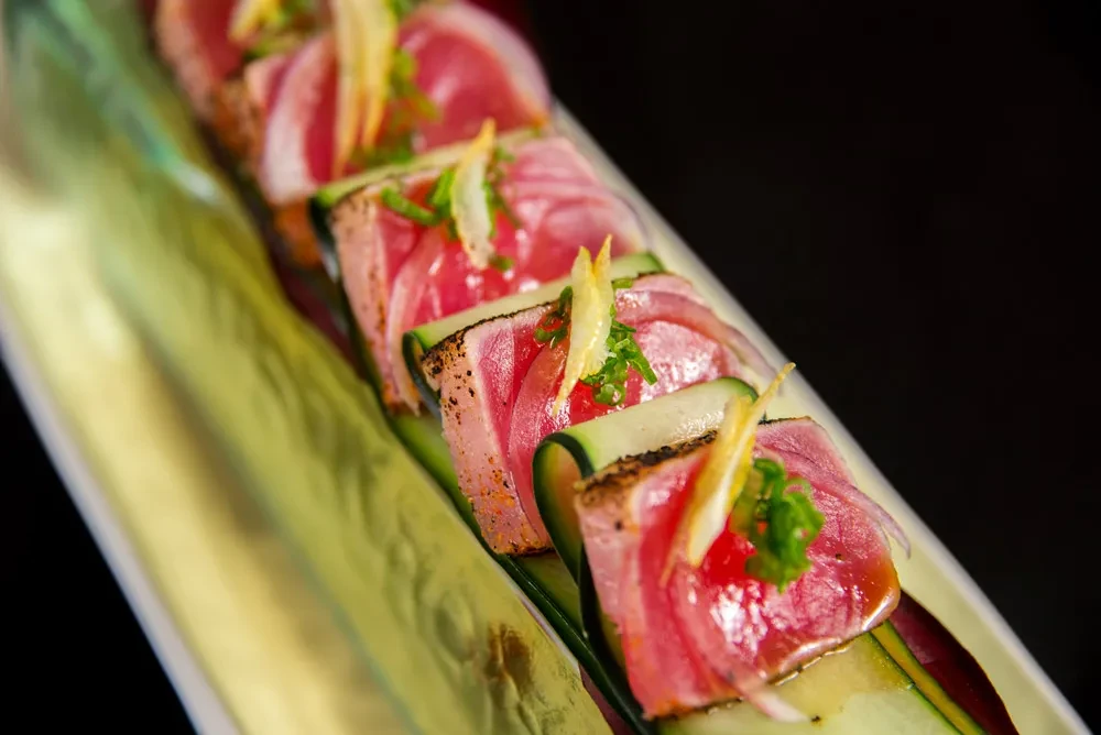 Seared tuna slices with cucumber, red onion, chives, and citrus zest.