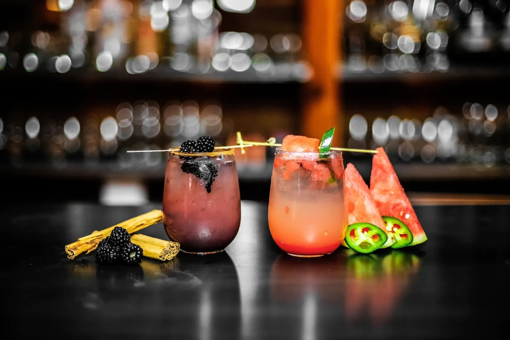 Two cocktails: purple with blackberries, red with watermelon and jalapeño.