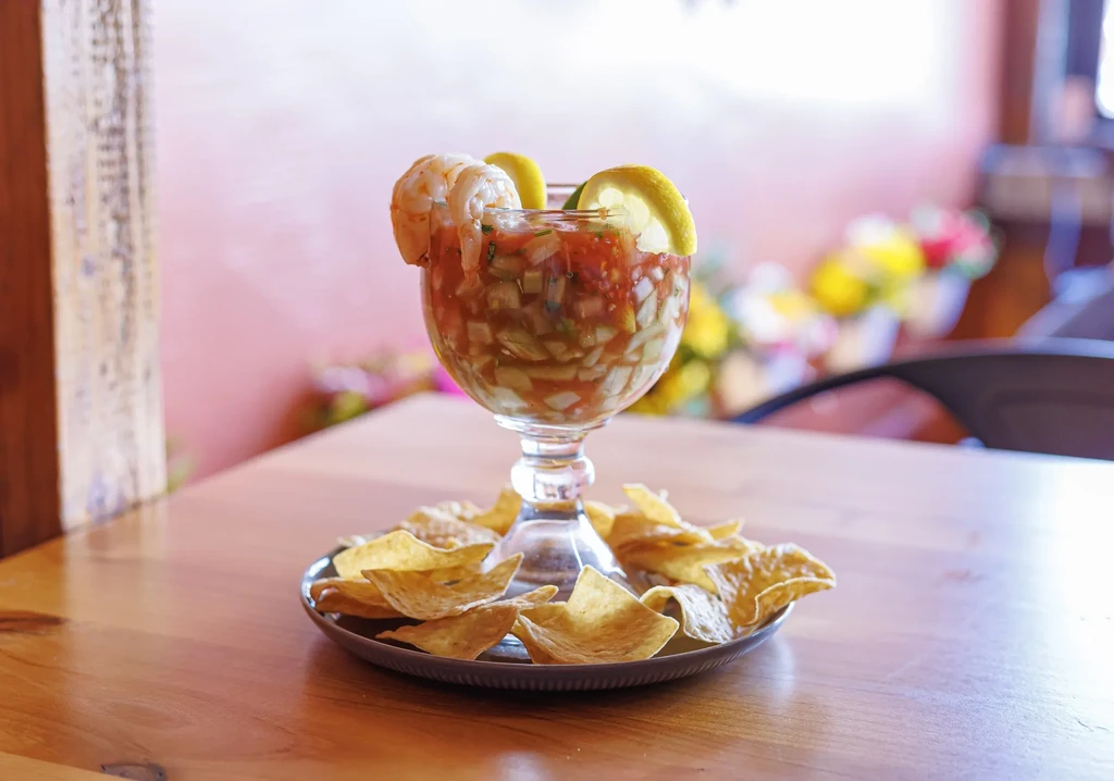 Shrimp and ceviche in a stemmed glass with tortilla chips.