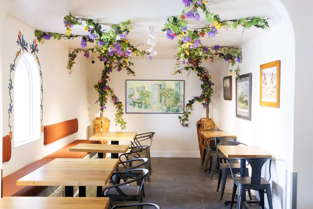 Bright, white restaurant interior with extensive colorful floral vines.
