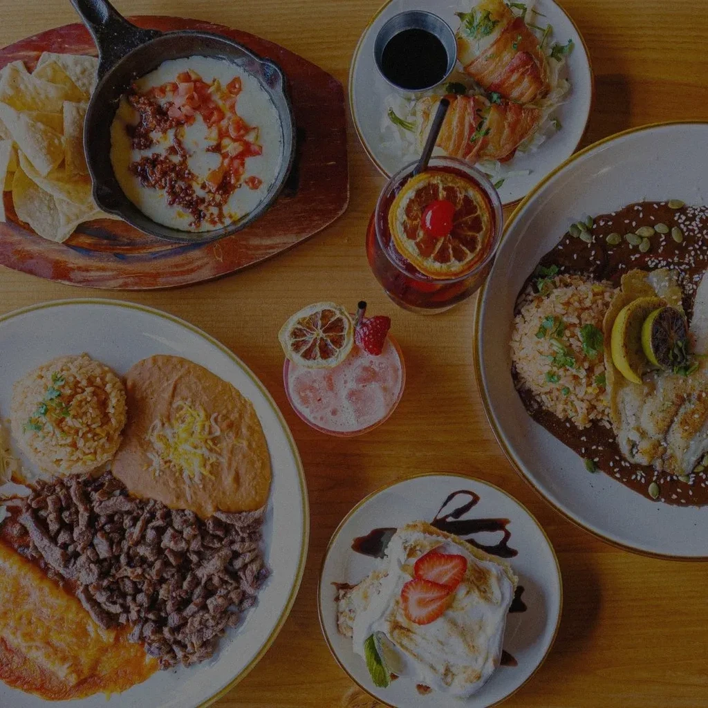 Overhead view of a diverse food and drink spread on a wooden table.