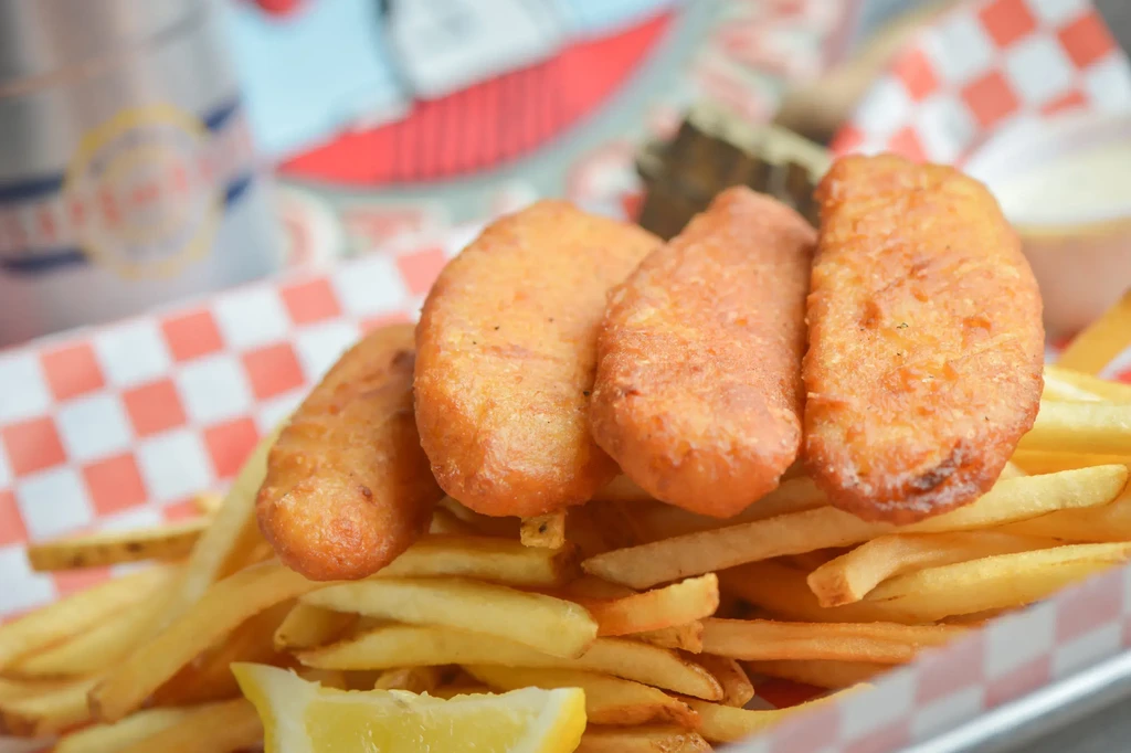 Golden battered food, fries, and lemon on checkered paper.