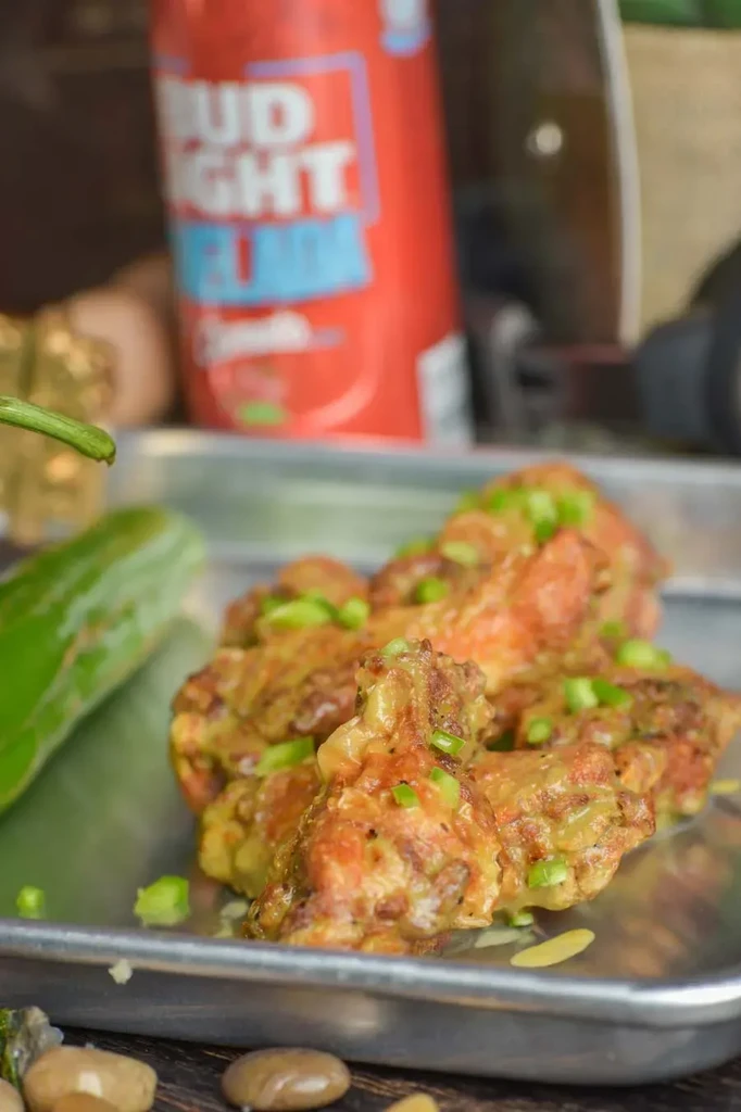Sauced chicken wings on a metal tray with Bud Light Seltzer.