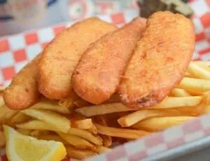 Golden battered fish and chips served with a lemon wedge.