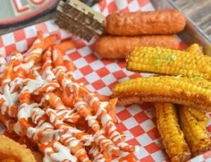 Diner tray with sauced curly fries, corn, and fried snacks.