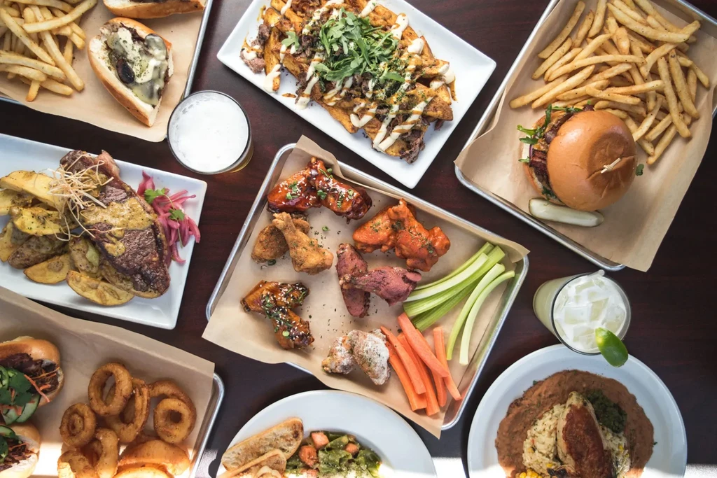 Overhead view of a table filled with diverse restaurant food and drinks.