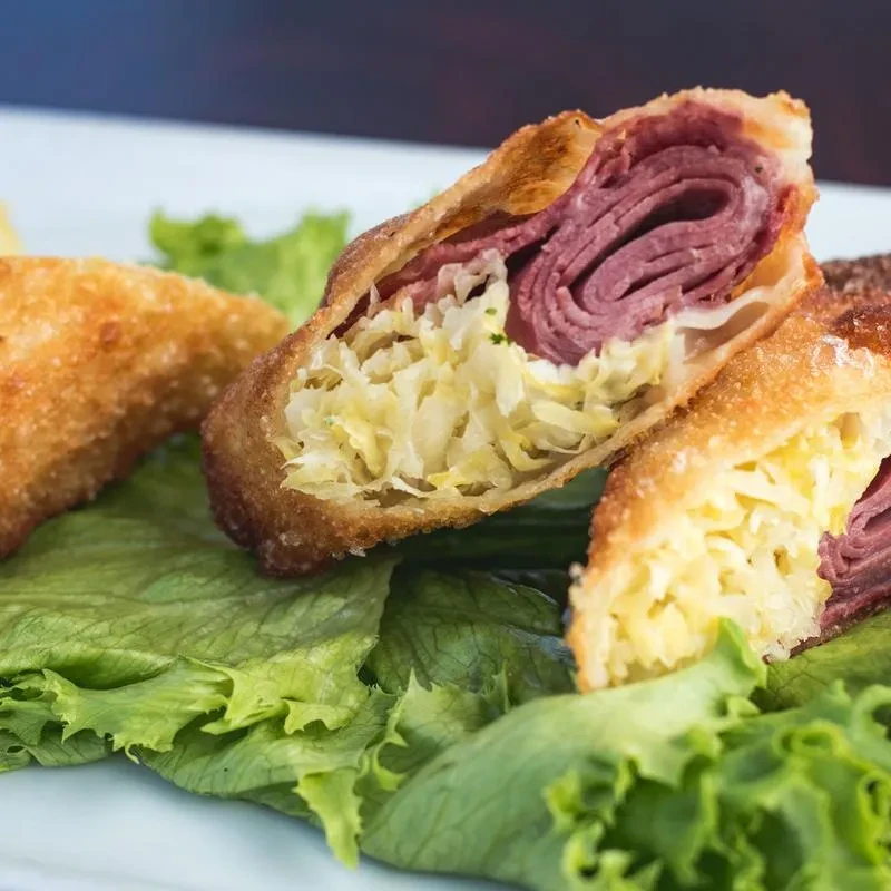 Golden-brown fried Reuben egg roll, sliced, with corned beef and sauerkraut.