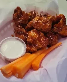 Glossy reddish-brown chicken wings, creamy dip, and carrot sticks.