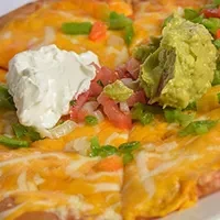 Sliced Mexican pizza with melted cheese, guacamole, sour cream, and pico.