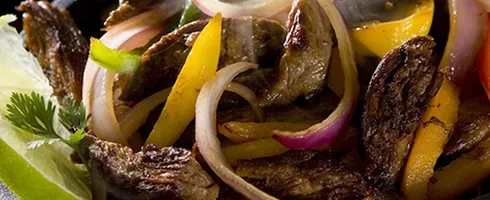 Seared meat, onions, yellow peppers, cilantro, and lime wedges.