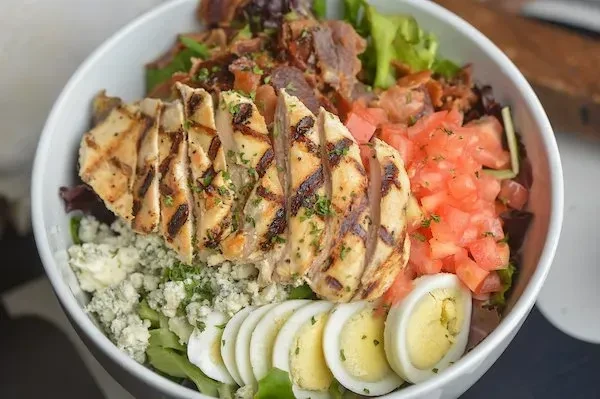 Close-up of a colorful Cobb salad with grilled chicken, eggs, and blue cheese.