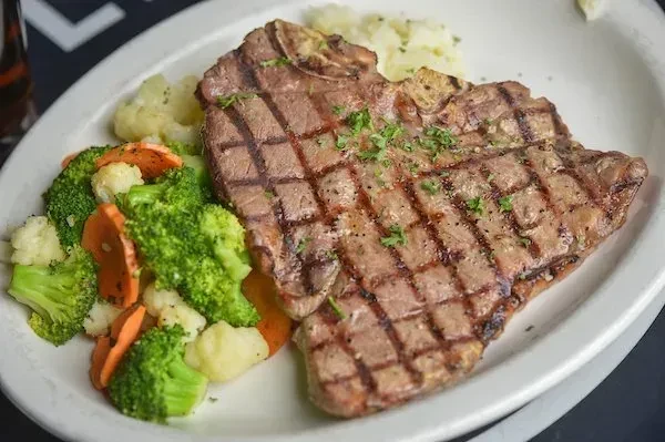 Grilled T-bone steak with mixed vegetables and mashed potatoes.