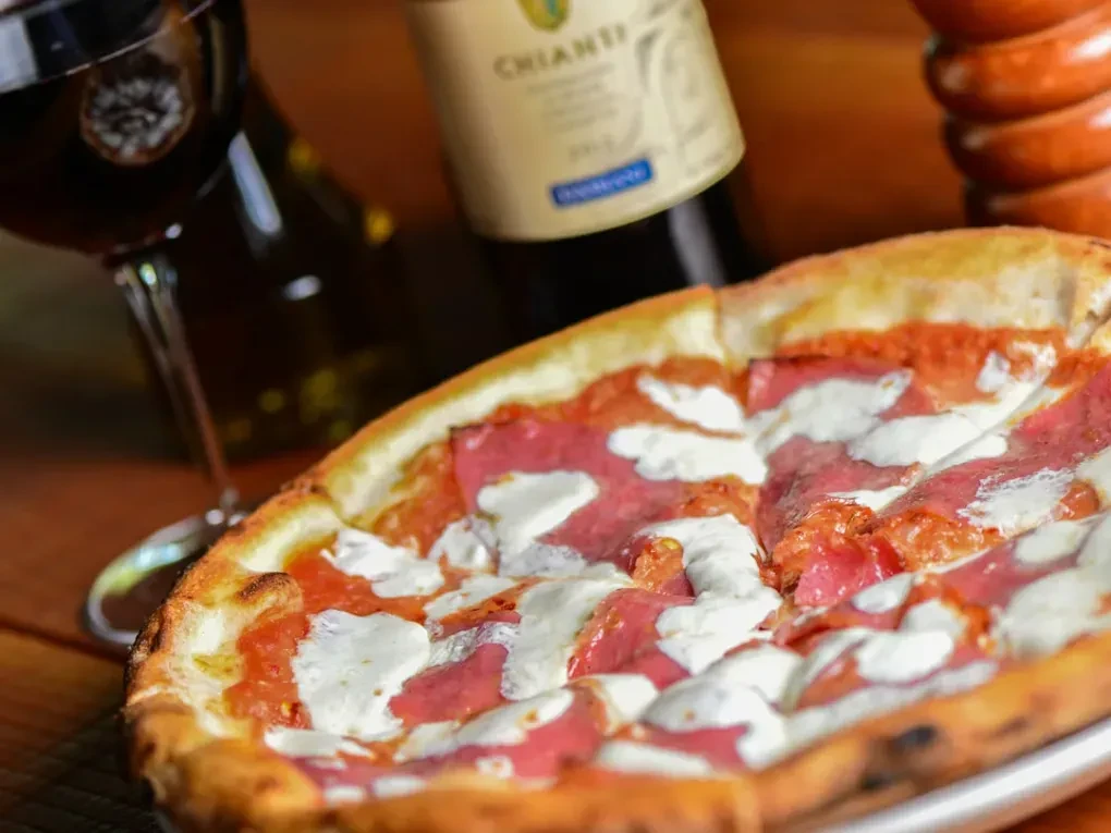 Freshly baked pizza with golden crust, red sauce, cheese, and cured meat.