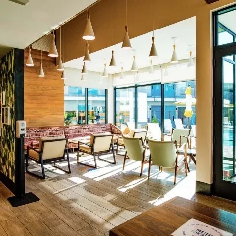 Modern lounge with patterned banquette, cone lights, and pool view.