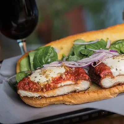 Sliced chicken parmesan sub with melted cheese, marinara, spinach, and onions.