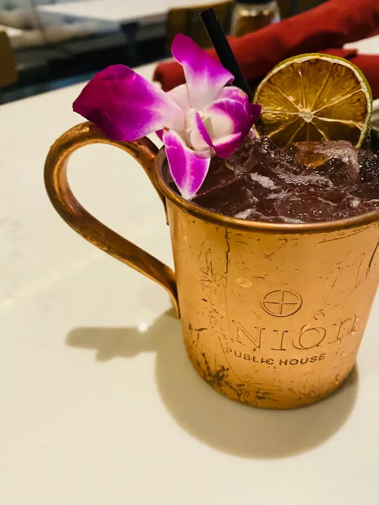 Union Public House cocktail in hammered copper mug with orchid garnish.