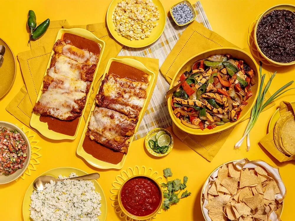 Overhead shot of a vibrant table with enchiladas, fajitas, and Mexican sides.