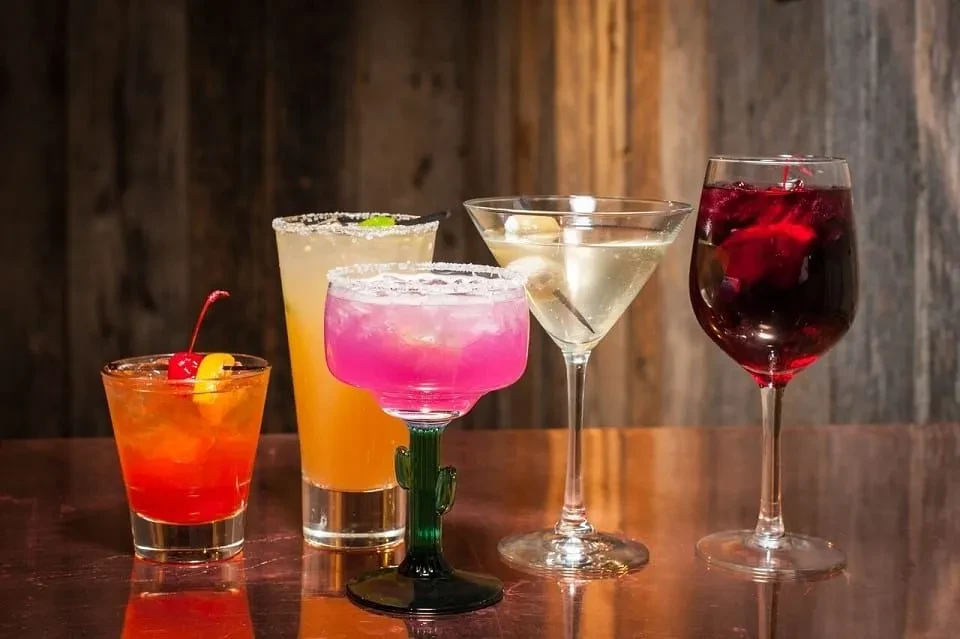 Five distinct, professionally prepared cocktails on a reflective surface.