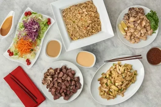 Overhead view of a diverse meal spread: salad, fried rice, steak, stir-fry.