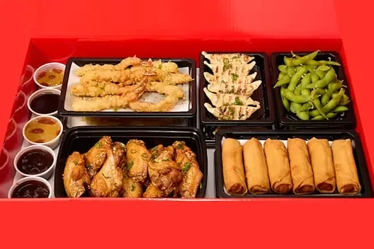 Colorful Asian takeout meal kit in black containers inside a red box.