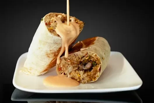 Burrito halves on a plate, rich filling, creamy orange sauce poured.