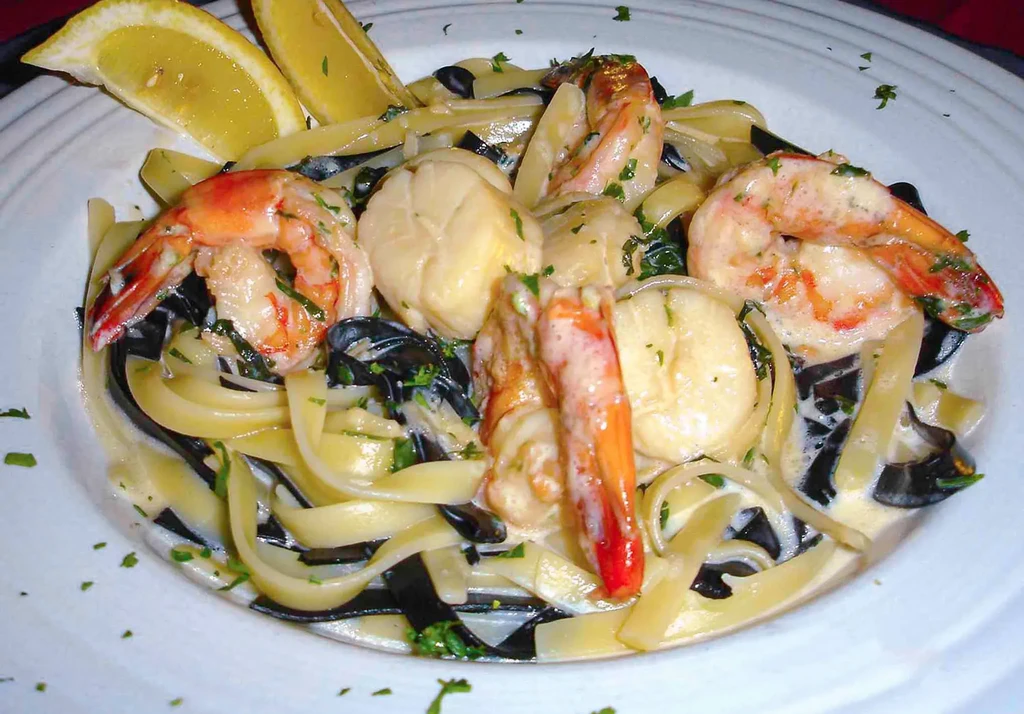 Close-up of creamy seafood pasta with shrimp, scallops, mussels, and lemon.