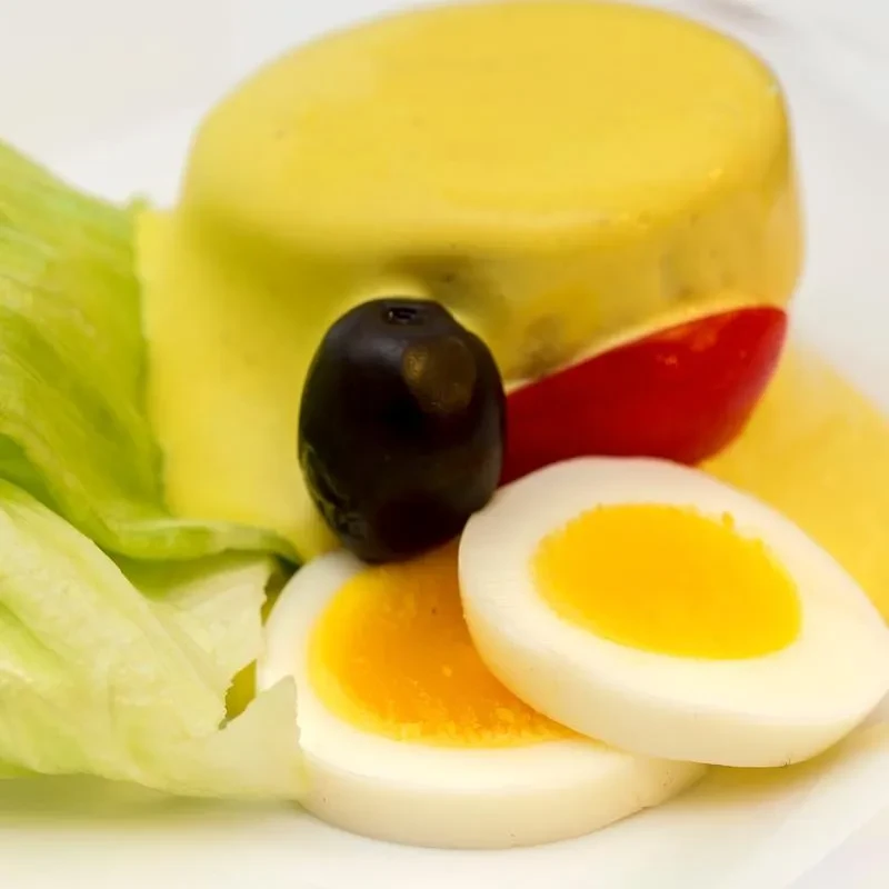 Plated yellow puree, black olive, hard-boiled egg halves, and lettuce.