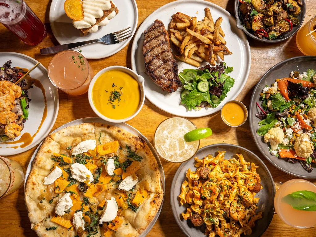 Overhead flat lay of diverse food and drinks on a wooden table.