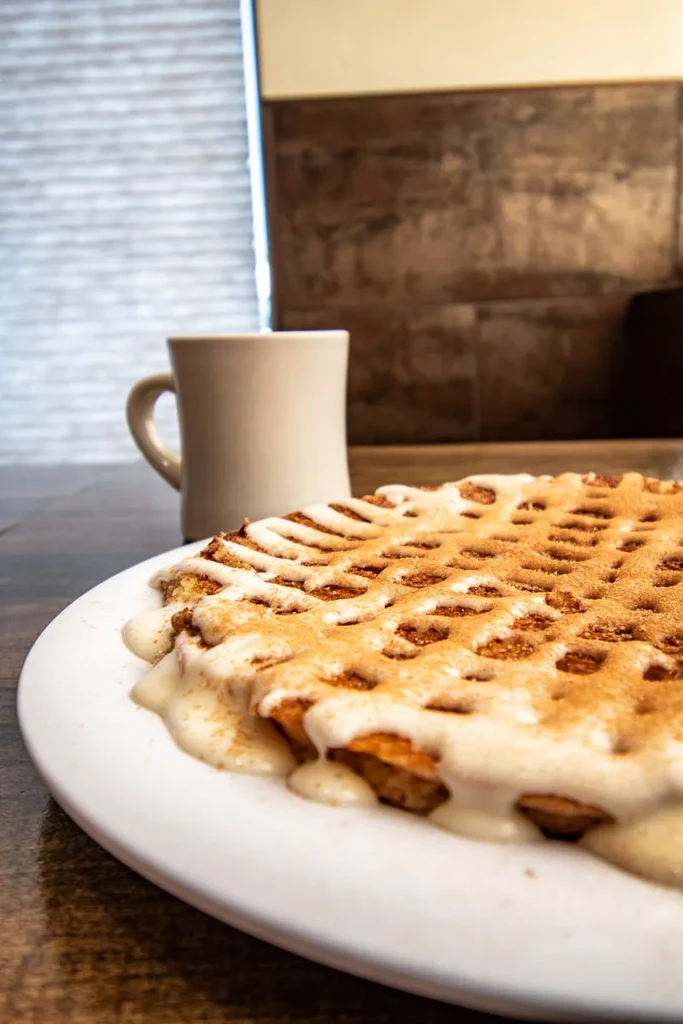 Golden-brown waffle, glazed white, sprinkled with cinnamon sugar.
